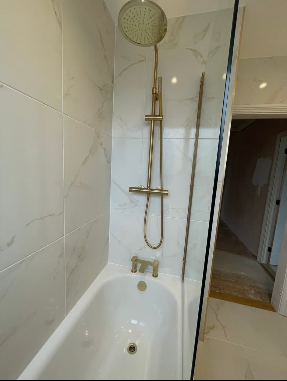 Marble-tiled bath and shower with brushed gold fixtures